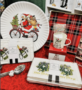 holiday themed cocktail napkins, a mug, spoons, and a plate with Santa