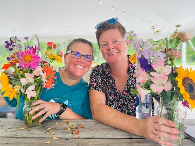The owners of Freckled Flower Farm stand with floral arrangements