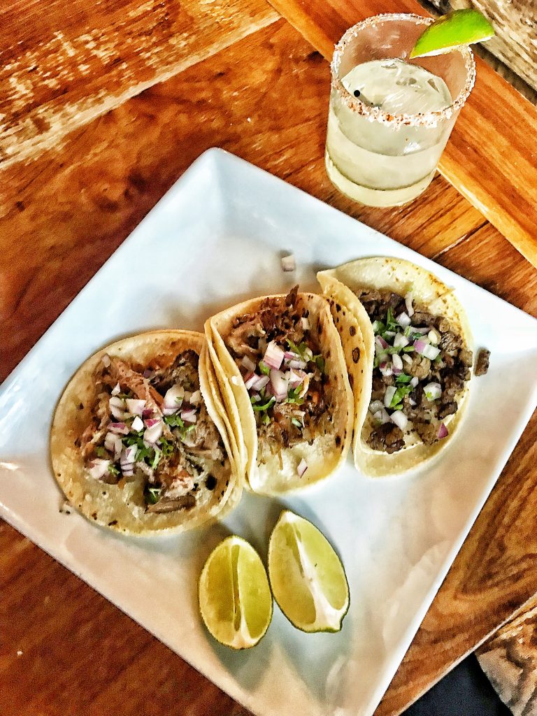 three tacos and a margarita on a table