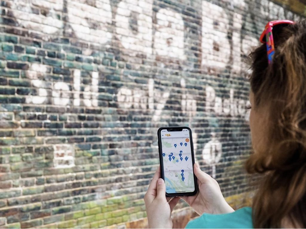 a girl holds a phone in front of a wall with pin points