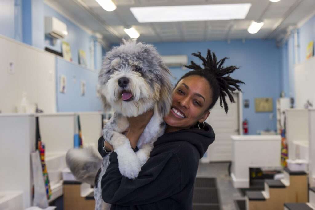 The owner of a Richmond pet grooming business holding a freshly groomed dog