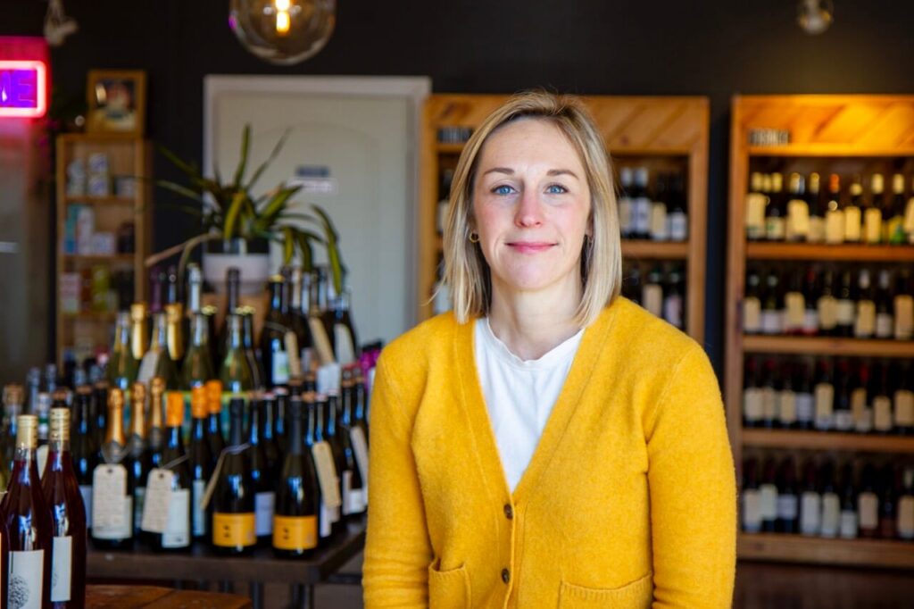 The owner of a Richmond neighborhood wine shop behind her counter