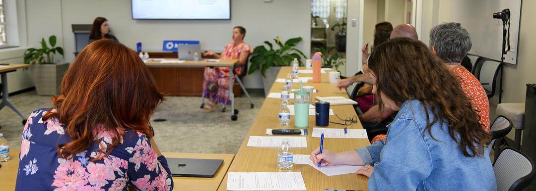 InUnison members seated around a table, taking notes while an expert leads a discussion